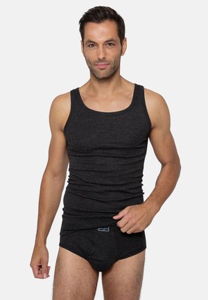 Débardeur noir à rayures horizontales, en matériau doux. Modèle portant des culottes noires assorties, mettant en valeur un design ajusté.