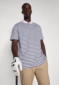 Polo shirt with purple and navy horizontal stripes, short sleeves, and a collar. Worn with beige pants and a white golf glove, holding a club.