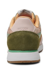 Zapatilla que combina varios materiales: suave cuero rosa, ante verde, malla naranja texturizada y una suela de goma blanca con un acabado texturizado.