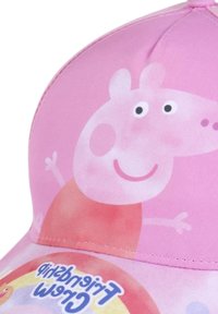 Casquette rose avec un design avant représentant un cochon de dessin animé avec un visage rond et les bras étendus ; détails brodés et un logo coloré à la base.