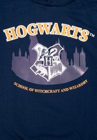 Felpa con cappuccio blu navy caratterizzata da una grafica di Hogwarts con uno stemma che mostra un leone, un serpente, un tasso e un'aquila, con "HOGWARTS" in testo arancione sopra.