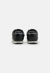 Black leather sneakers with a smooth finish, featuring white logo text on the heel and a contrasting white sole. Rounded design, minimal detailing.