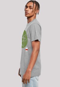 Camiseta de algodón gris con un gráfico de símbolo atómico verde y acentos de texto en rojo y blanco, con un corte relajado y cuello redondo.