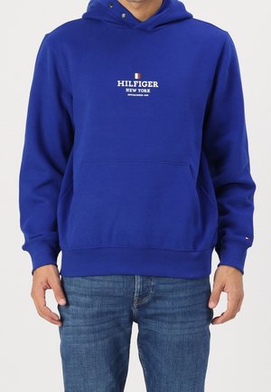 Niebieska bluza z kapturem, z przednią kieszenią kangurką, ściągaczami przy mankietach i u dołu, zdobiona białym logo "HILFIGER NEW YORK" oraz małą flagą akcentową.