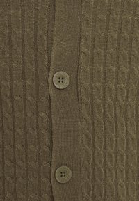 Oliwkowo zielony sweter rozpinany z fakturą splotu warkoczowego, ozdobionymi guzikami z grawerem "SOUL BRAVE" oraz prążkowanym kołnierzem i krawędziami.