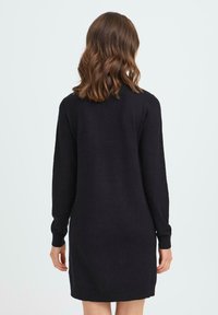 Vestido de punto negro con mangas largas, corte recto y cuello redondo. La tela parece suave con una textura lisa.