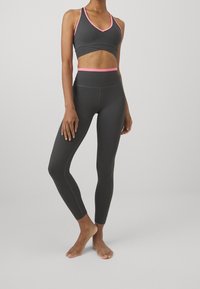 Šedý sportovní crop top s růžovými akcenty a odpovídajícími legínami s vysokým pasem, vyrobený z texturované elastické tkaniny, navržený pro aktivní nošení.
