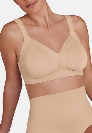 Beige seamless bra with wide straps, full coverage cups, and a smooth texture. Features minimal stitching detailing and a simple design.