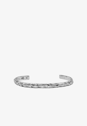 Hõbedast metallist mansetinööriga käevõru, millel on tekstuuriga vasardatud viimistlus. Avatud otsad ja sile sisemus, millel on peen brändi graveering.