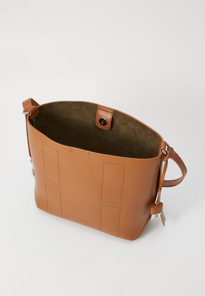 Tan leather tote bag with smooth texture, featuring a spacious interior, snap button closure, and minimalistic stitched accents.