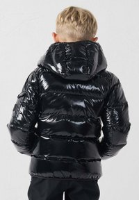 Chaqueta acolchada negra y brillante para niños con capucha, que presenta secciones acolchadas horizontales y un bolsillo lateral.
