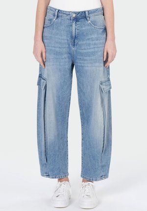 Light blue wide-leg jeans with side cargo pockets worn with white sneakers.