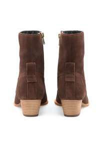 Bottines en daim marron avec fermetures éclair dorées, talon empilé et détail de boucle à l'arrière, présentant une texture lisse et une coupe ajustée.