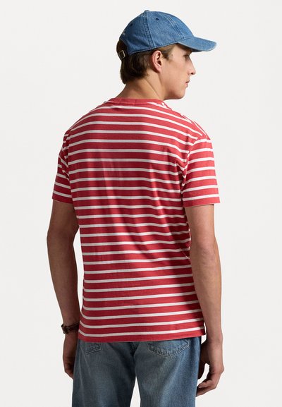 Röd och vit randig t-shirt med korta ärmar, rund hals, och ljusblå denimkeps, bärs tillsammans med ljus tvättade jeans.