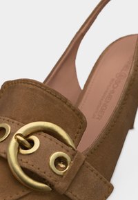 Καφέ σουέντ γόβα με λουράκι στον αστράγαλο, με χρυσή κυκλική αγκράφα και εμφανές ράψιμο στο λουράκι και το πάνω μέρος.