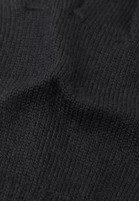 Czarna dzianina o gładkiej, gęstej strukturze i delikatnym połysku, prezentująca równomierne szwy i spójną kolorystykę w całej powierzchni.