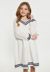 Weißes Kleid mit V-Ausschnitt, marineblauen gestreiften Akzenten am Kragen und den Ärmeln, langen Puffäßen und einem ausgestellten Rock. Glattes, leichtes Material.