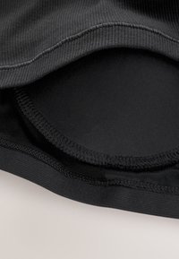 Black tank top with ribbed texture; features a smooth inner lining, neatly sewn edges, and a seamless design at the neckline and armholes.