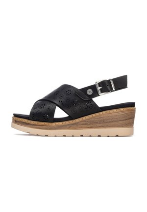 Sandalias de cuña de cuero negro con diseño floral recortado, hebilla ajustable y suela plataforma de madera clara con textura.