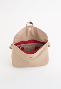 Beige læderhåndtaske med præget mønster, rød indvendig, guld hardware og en toplåse. Har en lynlåslomme og justerbar strap.