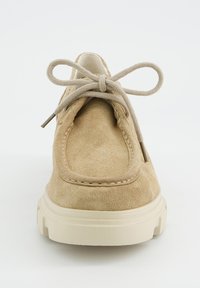 Chaussure décontractée en daim beige avec un bout arrondi, des coutures accentuées, une semelle blanche épaisse, et des lacets beiges noués en un nœud.