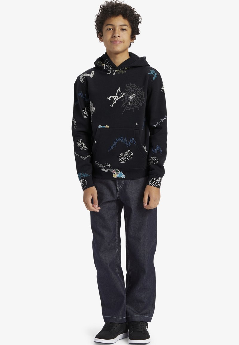 Svart hoodie med olika färgglada mönster, inklusive ett spindelnät, tärningar och olika grafik. Matchad med mörk denimjeans och svarta skor.