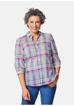 Camicia a quadri in colori pastello, con colletto, maniche a tre quarti e vestibilità rilassata. Indossata con jeans blu.