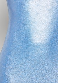 Snyggt blått passande tyg med en strukturerad, glittrande yta. Gradvis färgvariation från ljus till mörkblå. Inga mönster eller hårdvara synlig.