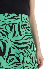 Zwarte en groene gestreepte rok met abstracte, vloeiende lijnen op een teal basis; zachte stof met een gladde textuur en gestructureerde vorm.