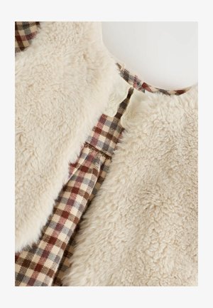 Krémová umelá kožušina s vnútorným podšívkou v károvanom hnedom, červenom a modrom vzore. Okrúhly výstrih s hladkým povrchom a jemnou textúrou.