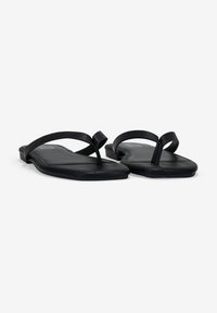 Chanclas negras con suela plana, que presentan un diseño minimalista y tiras de goma delgadas. Plantilla con textura para mayor comodidad y agarre.
