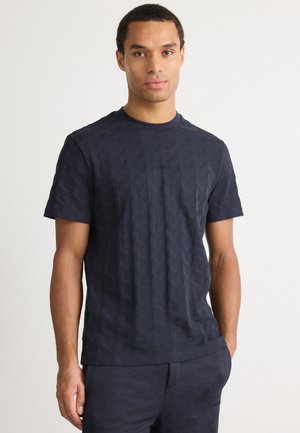 T-shirt blu navy a maniche corte con motivo geometrico testurizzato. Realizzato in cotone, presenta un collo rotondo e un logo sottile sul petto.