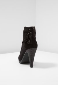Bottines noires à talons hauts en daim, avec un talon texturé, un détail de frange et un bout arrondi.