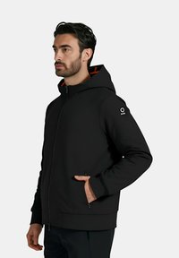 Felpa nera con zip e vestibilità strutturata, dotata di un rivestimento arancione a contrasto, due tasche laterali e un logo accentato sulla manica.