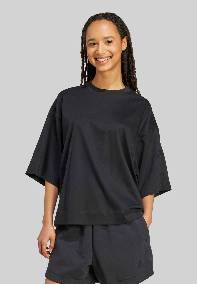Sort bomulds T-shirt med korte ærmer, afslappet pasform og rund hals, med en diskret logoaccent på ærmet. Sammen med matchende shorts.