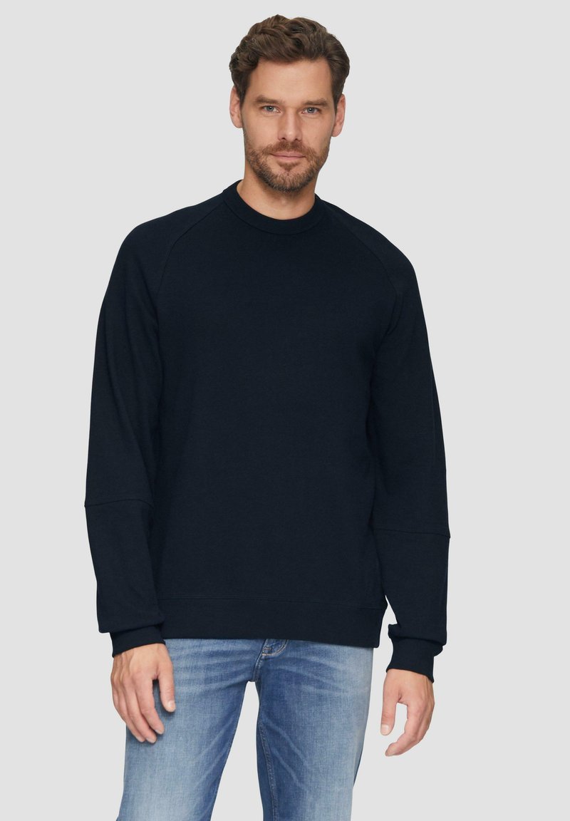 Tmavě modrý crewneck svetr s vroubkovanými manžetami a lemem. Vyroben z měkkého materiálu s uvolněným střihem a designem raglánových rukávů. Osobitý styl.
