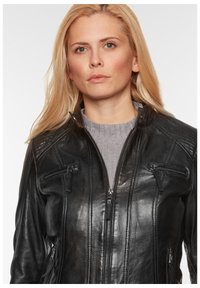 Schwarze Lederjacke mit einem Reißverschluss vorne, schrägen Reißverschlusstaschen, gerippten Schulterdetails und glatter Textur, getragen über einem grauen Pullover.