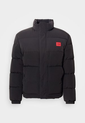Black puffer jacket with high collar, front pockets, and red "HUGO" logo patch on left chest.