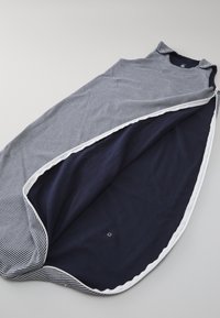 Marineblå og hvit stripete sovepose med glatt stoff, rund utringning og hvit piping langs åpningen, som avslører en ensfarget marineblå innside.