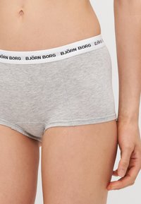 Sive pamučne bokserice s crno-bijelim pojasom oznake "BJÖRN BORG." Tkanina izgleda mekano s blagom teksturom.