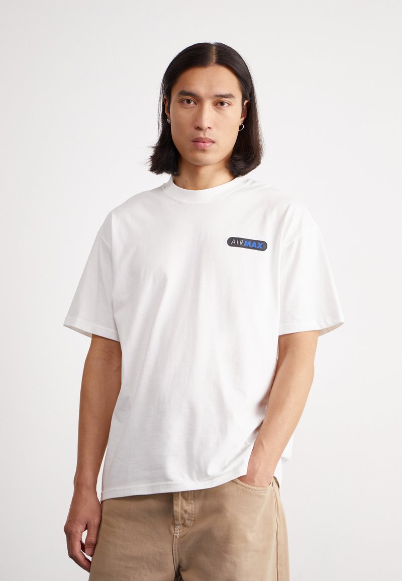 Balta medvilnė t-shirt su laisvu siluetu, apvaliu iškirpimu ir trumpomis rankovėmis. Kairėje krūtinės pusėje yra mėlynas "AIRMAX" logotipas.
