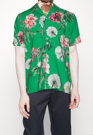Camisa de manga corta de tela verde con grandes patrones florales en rosa, blanco y verde. Detalles de botones notables y un ajuste relajado.