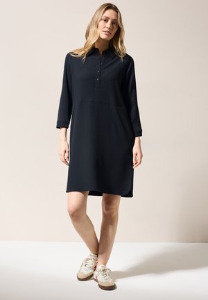 Navyblauwe jurk tot de knie met een kraag, driedubbele knopen en lange mouwen. Texturized stof met een ontspannen pasvorm.
