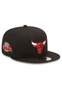 Schwarze Kappe mit flachem Schirm, auf der Vorderseite mit einem roten gestickten Chicago Bulls-Logo und auf der Seite mit einem runden Champions-Patch versehen.