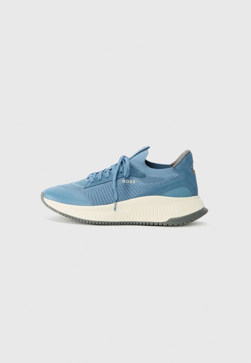 Light blue athletic shoe with a textured knit upper, lace-up design, and contrasting white sole with grey accents. Logo on the side.