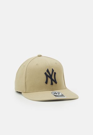 Casquette de baseball beige avec le logo des New York Yankees brodé en bleu marine à l'avant et une visière plate ornée d'un autocollant blanc '47 Captain'.