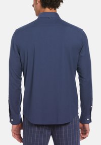 Navy blue long-sleeve shirt with a button-down collar, smooth fabric, and curved hem, featuring buttoned cuffs and a subtle back accent.