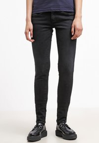Czarne skinny jeans o gładkiej teksturze denimu, pięciokieszeniowym kroju i średnim stanie, połączone z czarnymi sznurowanymi butami na platformie.
