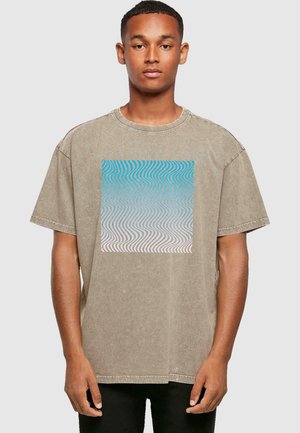 Khaki oversized t-shirt i blødt stof med et blåt og hvidt tekstureret bølgemønster på forsiden. Rund hals og korte ærmer.