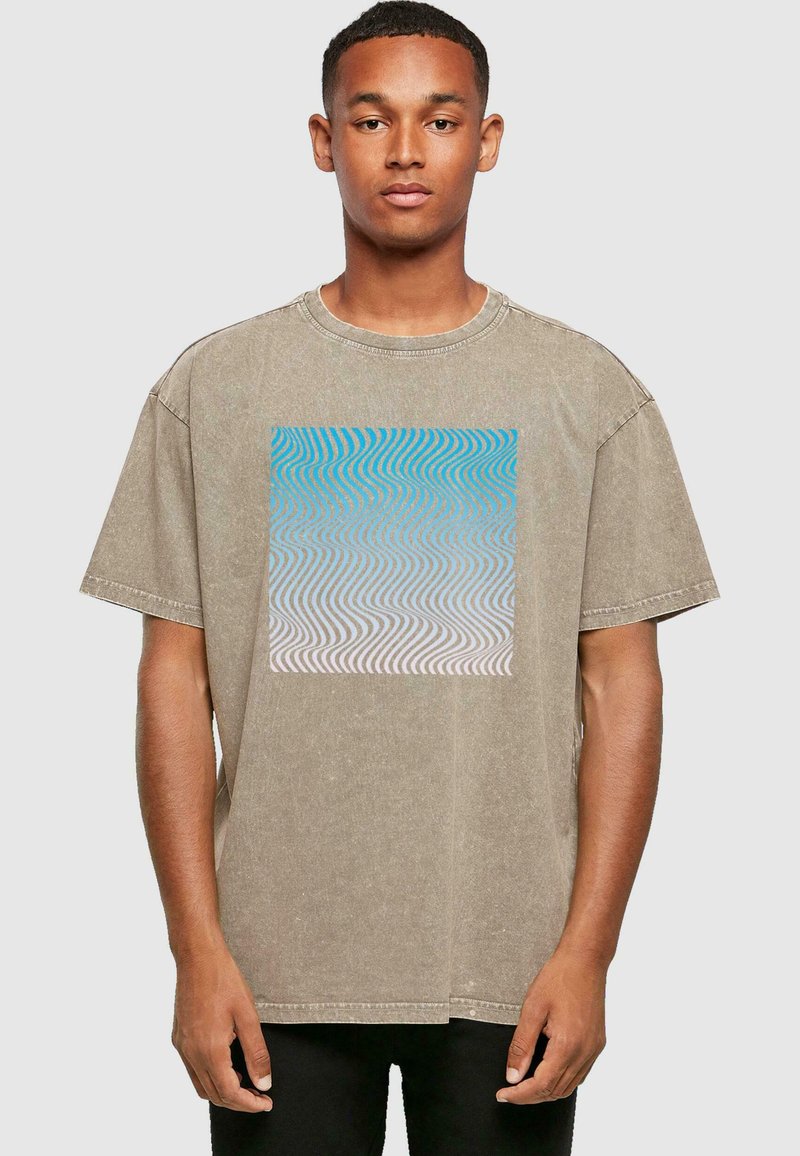 Khaki oversized t-shirt i blødt stof med et blåt og hvidt tekstureret bølgemønster på forsiden. Rund hals og korte ærmer.